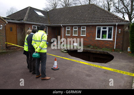 Surveyors at the home of Phil and Liz Conran, in Main Road, Walter's Ash, High Wycombe, Buckinghamshire, after a 30ft-deep sinkhole opened up in the driveway yesterday and swallowed his car. Stock Photo