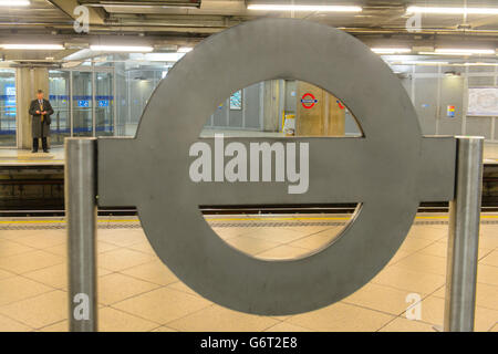 A man waits on the platform, beyond a sign, at Westminster Underground station, in central London, during a 48-hour tube strike as London Underground workers strike over planned job cuts and ticket office closures. Stock Photo