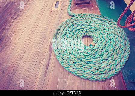 Vintage toned wide angle picture of mooring rope on wooden deck of a sailboat. Stock Photo