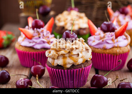Different delicious cupcakes decorated with caramel and fresh berries Stock Photo