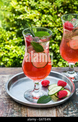 Pink gin and tonic cocktail with raspberries, cucumber and mint Stock Photo