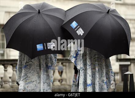 London Fashion Week stewards converse under their umbrellas at Somerset House on day one of London Fashion Week. Stock Photo