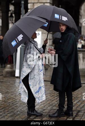 London Fashion Week stewards converse under their umbrellas at Somerset House on day one of London Fashion Week. Stock Photo