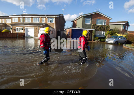 Members of the Surrey Fire and Rescue Service make adjustments to a high volume pump (HVP) to remove water from a housing estate in Staines-upon-Thames. Stock Photo