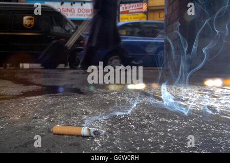 A cigarette on the pavement ban on smoking in the work place Stock Photo