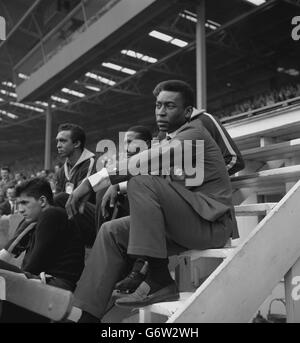Brazilian footballer Pele (r), still feeling the effects of injuries sustained in a crash in Hamburg, sits in the stand during the international friendly against England at Wembley Stadium, London. Just before kick-off, a near-capacity crowd booed the announcement that Pele would not be playing. The match ended 1-1. Stock Photo