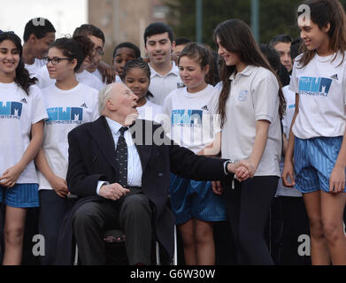 Sir Roger Bannister poses with local children during a photocall at Paddington Recreation Ground, London. Stock Photo