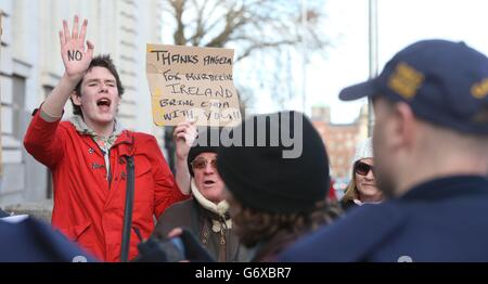 A protestor is seen as German Chancellor Angela Merkel and Taoiseach Enda Kenny arrive for a press conference at Government Buildings in Dublin today. Stock Photo