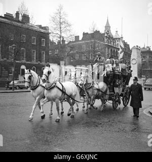 A stage coach, flying the flag of St George, travels along Whitehall during St George's Day celebrations. On the box is a top-hatted driver and 50 women in hot pants, while inside the box there are Epping sausages, made from an old English recipe, destined for the Prime Minister at 10 Downing Street. After the traditional delivery, the women plan to find 4,000 rose-wearers in and around London to treat them to a pint of English ale on behalf of St George's Taverns Limited. Stock Photo