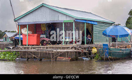 Woman using a motorized grinder on a house boat, Tahas River in a light rain, Tonle Sap, Cambodia Stock Photo