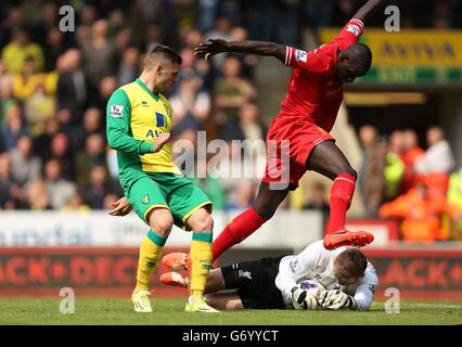 Liverpool's Simon Mignolet saves at the feet of team mate Mamadou Sakho and Norwich City's Gary Hooper Stock Photo