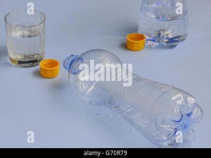 two bottles of water drained ,with orange cap and the glass Stock Photo
