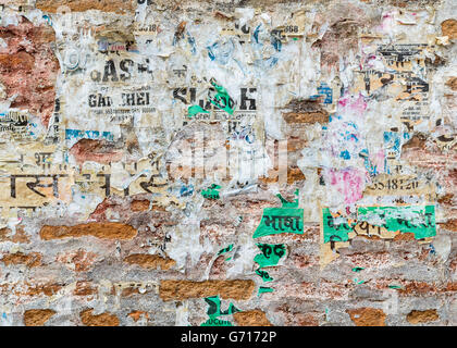 Grungy brick wall texture with torn posters in Kathmandu, Nepal Stock Photo