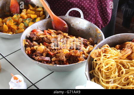 Metal bowls of potatoes, beef and chicken and noodle dishes at a market in Peru Stock Photo