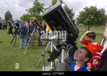 Eoin Conran, 8, from Dublin, looks towards the sun through a telescope to see the planet Venus passing across its face in a rare event in the astronomical calendar, at Phoenix Park in Dublin, Ireland, as his sister Aisling, 6, looks on. It was the first Venus transit since 1882 and the last time it was observable from the UK was in 1283 - long before the invention of the telescope. Earth's closest planetary neighbour appeared as a black disc 30 times smaller than the Sun's diameter, slowly moving from left to right over the course of six hours. Stock Photo