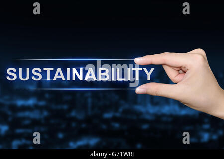 hand pushing sustainability button on blurred blue background Stock Photo