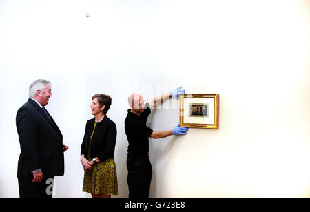 Gallery director Barbara Dawson in conversation with Detective Chief Superintendent Chief Bureau Officer at the Criminal Assets Bureau Eugene Corcoran as art handler Clive Bermingham adjusts 'In the Omnibus' by the French artist Honore Daumier (1808 - 1879) at Dublin City Gallery The Hugh Lane as the gallery together with Criminal Assets Bureau announce it's return following it's theft from the gallery. Stock Photo