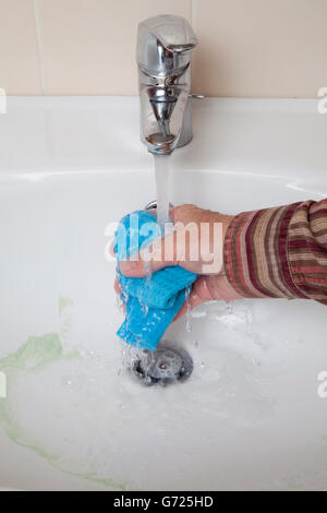 Sink being cleaned, running tap water, hand washing out sponge cloth Stock Photo