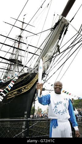 Former athlete Kriss Akabusi carries the torch from The Cutty Sark, at Cutty Sark Gardens, London, on the 23rd leg of the Olympic Torch Relay 2004. Stock Photo