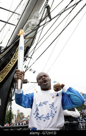 Former athlete Kriss Akabusi carries the torch from The Cutty Sark, at Cutty Sark Gardens, London, on the 23rd leg of the Olympic Torch Relay 2004. Stock Photo