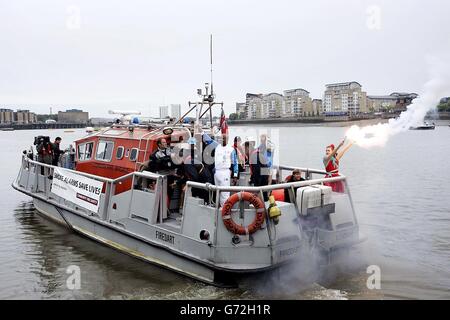 Former athlete Kriss Akabusi carries the torch across the River Thames by boat from Cutty Sark Gardens, London, on the 23rd leg of the Olympic Torch Relay 2004. Stock Photo