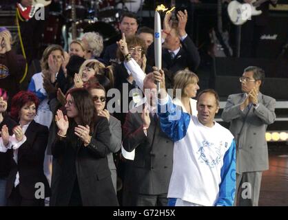 Olympic gold medallist Sir Steven Redgrave carries the Olympic torch on stage, as Sharon, Ozzy and Jack Osbourne look on, at the Olympic Torch Concert in The Mall, central London a free concert organised by Visit London and The Greater London Authority to celebrate the arrival of the Olympic torch in London. Stock Photo