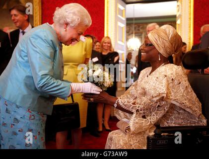 Queen Elizabeth II receives flowers from Veronica Thomas during a reception for Leonard Cheshire Disability in the State Rooms, St James's Palace, London. Stock Photo