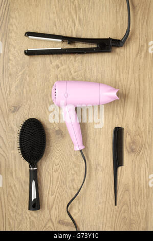Hair dryer, comb, scissors, iron and brush on wooden background Stock Photo