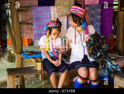 A Padaung mother (long neck women) sharing a moment with here daughter, Thailand. Stock Photo