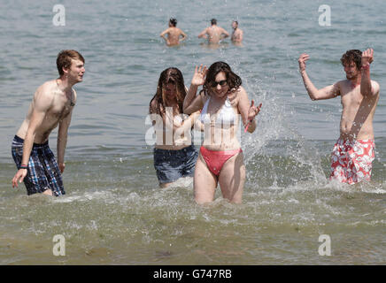 Festival goers Zoe Abbott (centre) and Rachel Gates (centre left) getting splashed by water from their friends in the sea at the beach in Ryde, before heading to the Isle of Wight Festival. Stock Photo