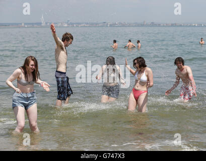 Festival goer Zoe Abbott (centre) getting splashed by water from their friends in the sea at the beach in Ryde, before heading to the Isle of Wight Festival. Stock Photo