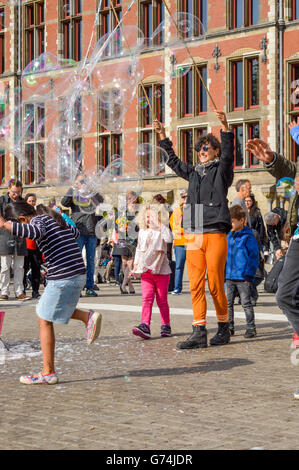 AMSTERDAM - SEPTEMBER 18, 2015: Woman making huge bubble balloons on a public square Stock Photo
