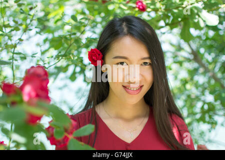 Woman in red dress with a red rose in her hair Stock Photo