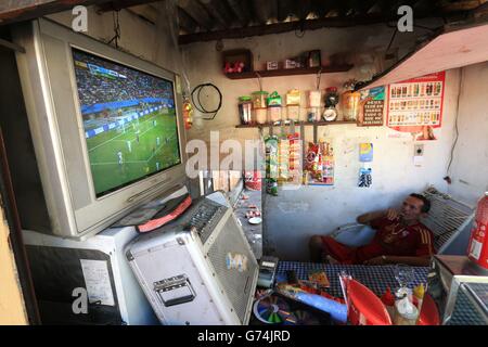 Soccer - FIFA World Cup 2014 - Fans. A local shopkeeper watches the Netherlands v Spain match on a television inside a small shop outside the Arena da Amazonia, Manaus, Brazil. Stock Photo