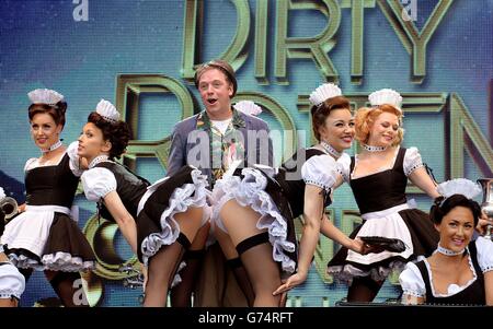 Rufus Hound (3rd left) singing with the chorus line of the show Dirty Rotten Scoundrels during a performance at the annual West End Live weekend in Trafalgar Square, London, where people watched entertainers from West End productions perform for free. Stock Photo