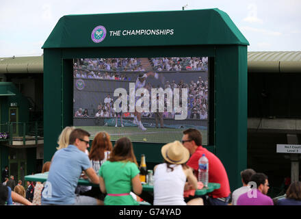 Fans enjoy the view of the big screen outside court one on Murray mount during day four of the Wimbledon Championships at the All England Lawn Tennis and Croquet Club, Wimbledon. Stock Photo