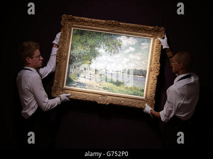 Gallery staff holding a work by Claude Monet, La Seine a Argenteuil, 1875, which is estimated at £7-10 million, during a photocall for Sotheby's £250m Impressionist & Modern Art and Contemporary Art Summer Sales in New Bond Street, London. Stock Photo
