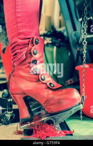 Red boot on sewing machine pedal Stock Photo