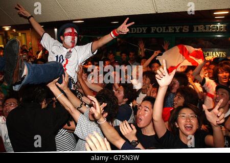Japanese football fans supporting England celebrate outside Paddy Foley's Irish bar in the Roppongi area of Tokyo, Japan after fans celebrated Englands 1-0 win against Argentina. Stock Photo