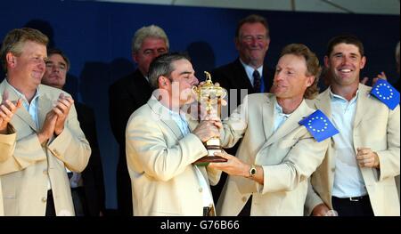 Europe's Paul McGinley (centre) kisses the Ryder Cup with team-mates Colin Montgomerie (left) Bernard Langer and Padraig Harrington (right) watching on during the presentation ceremony, after Europe defeated USA in the 34th Ryder Cup at the Belfry, near Sutton Coldfield. 30/09/02 : Europe's top golfers were celebrating their victory after lifting golf's 34th Ryder Cup, beating the United States in a thrilling contest. Little known Irish golfer McGinley sank a stunning 18ft winning putt to complete a famous triumph at The Belfry in Sutton Coldfield, West Midlands. Non-playing team captain Sam Stock Photo