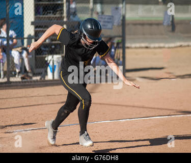 Softball player in black uniform sprinting to first base Stock Photo