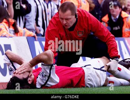 Arsenal's French international Robert Pires in pain while he is attended to by physio Gary Lewin with a injury to his right knee during the FA Cup sixth round replay match against Newcastle United at Arsenal's Highbury stadium in London. . 25/03/02 : Pires was today, ruled out of Arsenal's double bid and France's attempt to retain the World Cup this summer. The 29-year-old French international has sustained serious cruciate knee ligament damage and will be sidelined for several months. Stock Photo