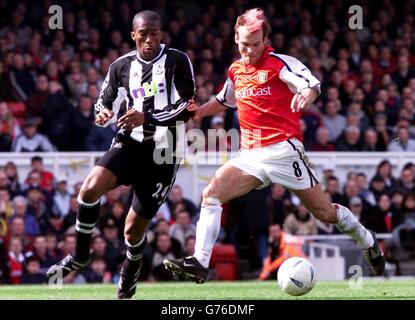 Arsenal's Fredrik Ljungberg (R) is challenged by Newcastle United defender Sylvain Distin during their FA Cup sixth round replay match at Arsenal's Highbury stadium in London. Stock Photo