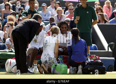 USA's Serena (right) receives treatment alongside sister Venus Williams before their doubles match on day nine of the Wimbledon Championships at the All England Lawn Tennis and Croquet Club, Wimbledon. Stock Photo