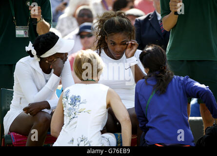 Tennis - 2014 Wimbledon Championships - Day Nine - The All England Lawn Tennis and Croquet Club. USA's Serena (right) receives treatment alongside sister Venus Williams before their doubles match Stock Photo