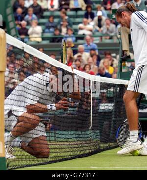 EDITORIAL USE ONLY, NO COMMERCIAL USE. The Argentinian David Nalbandian (left) runs into the net during his match against Xavier Malisse of Belgium in the semi-final on Court One at Wimbledon today Friday 5th July 2002. Malisse contraversialy left the court for ten minutes to receive medical attention after losing the first set tie break. Stock Photo