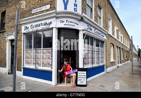 Textile artist Lucy Sparrow sits outside her art installation, The Cornershop in Wellington Row, Bethnal Green, east London, as she finishes of a giant tube of Parma Violets, as nearly 2,000 classic groceries inside are handmade from felt and are for sale as an art work. Stock Photo