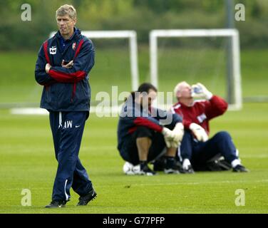 Arsenal manager Arsene Wenger (left) appears in deep thought whilst walking, as goalkeeper David Seaman (centre) sits alongside goalkeeper coach Bob Wilson during a training session at Arsenal's training ground, London Colney, Hertfordshire. * Arsenal will play Auxerre in their Champions League Group A match. Stock Photo