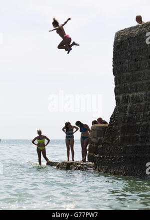 People jump off the sea defences into the water in Brighton, East ...