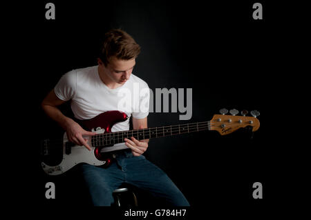 A teenage boy practices his bass guitar Stock Photo